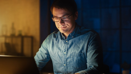 Professional Man Sitting at His Desk in Office Studio Working on a Laptop in the Evening. Man...