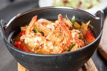 Chilli Soup with Shrimp or Tom Yum Kung is a popular Thai food and has a worldwide reputation, there is a hot and spicy taste of Thai identity and many ingredients with herb and serve in black bowl.