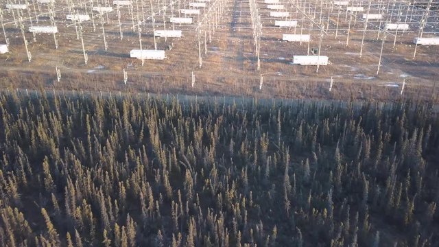 HAARP facility aerial reveal, high angle view of Alaskan forest tilt up to show Aurora Antennae