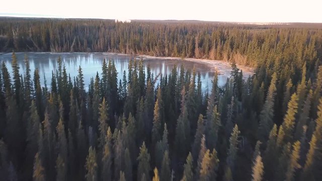 Flying over frozen Alaska lake and rising over trees to reveal HAARP government research base in distance