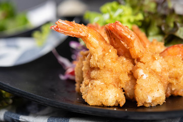 Crispy shrimp salad is prepare by bringing fresh shrimp to a crispy flour served with fresh vegetables on black dish. Suitable for supplement with a main course In order to receive complete nutrition