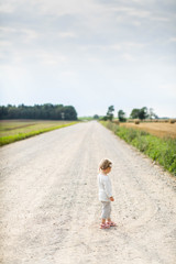 Little girl on the road in countryside. Summer.