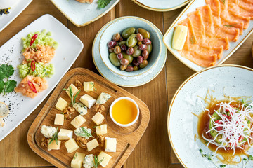 Cheese plate. Focus on delicious cheese mix with walnuts, honey on wooden table. Various snacks and antipasti on the table. Restaurant menu.