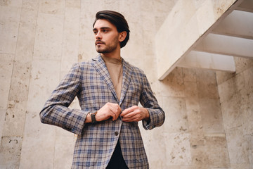 Young handsome man in checkered jacket thoughtfully looking away outdoor