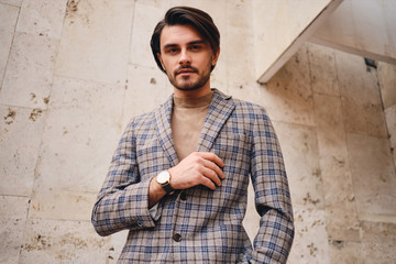Young handsome man in checkered jacket confidently looking in camera outdoor
