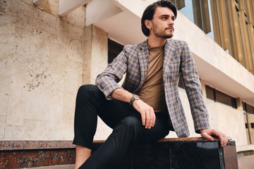 Young attractive man in checkered jacket confidently looking away outdoor