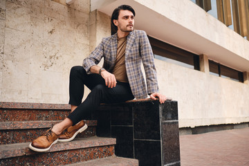 Young handsome man in checkered jacket thoughtfully looking away outdoor
