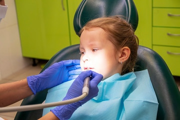 Little Caucasian girl treats teeth at the dentist