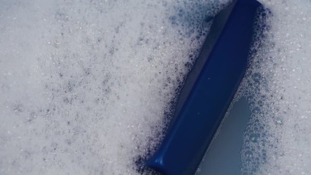 A blue can of shampoo floats in foamy water. The concept of cleanliness and personal care.