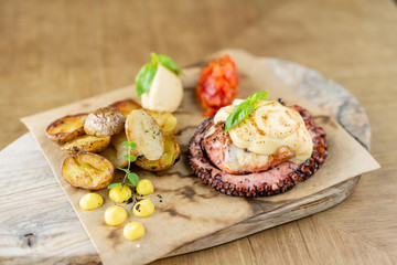 Roasted octopus BBQ with Baked potato. Wooden plate. Restaurant menu
