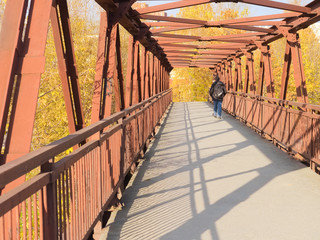 Lonely man crossing a steel bridge on an autumn day