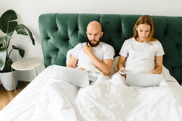 Obraz premium young couple using laptop together in bed 