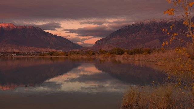 Mountains reflection in glassy lake at sunset panning over the landscape at Utah Lake.