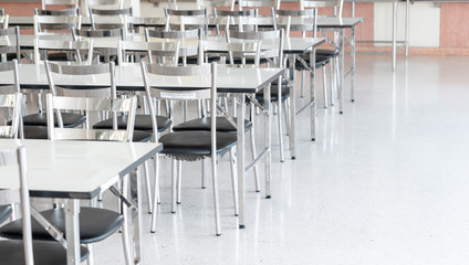 Stainless steel tables and chairs in high school student canteen, public cafeteria room interior background