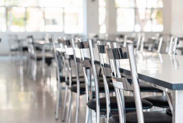 Stainless steel tables and chairs in high school student canteen, public cafeteria room interior background