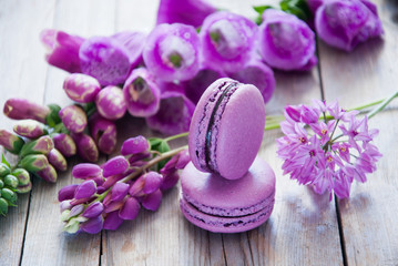 Fototapeta na wymiar Purple flowers and macaroon on a wooden background