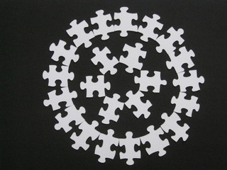 Círculos concéntricos, uno dentro de otro, hechos con piezas de puzzle blancas sobre fondo negro
