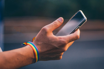 Hands of man with gay flag holding an smartphone