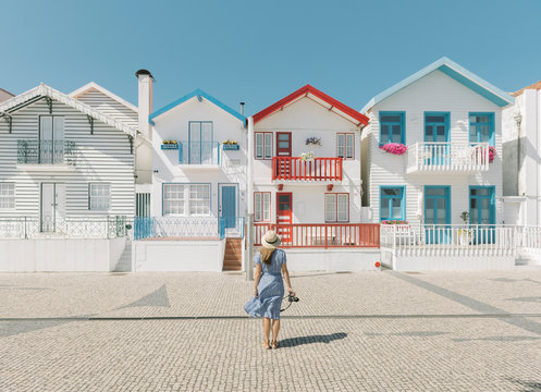 Rear view of woman with camera in front of houses, Costa Nova, Portugal
