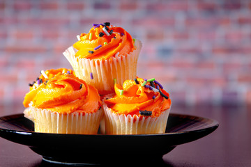 Halloween muffins on a black plate with a brick background 