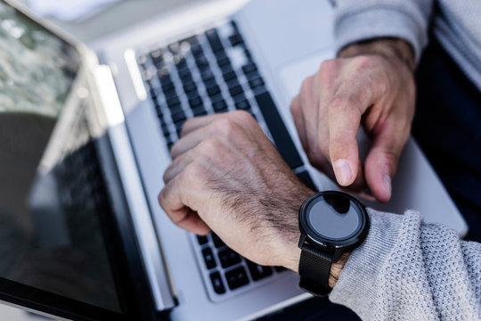 Close-up of man with smartwatch and laptop