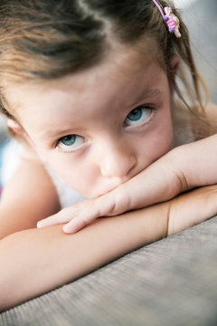 Sad looking little girl lying on sofa, close-up
