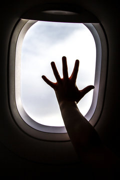 Silhouette of girl's hand on window on board of an airplane