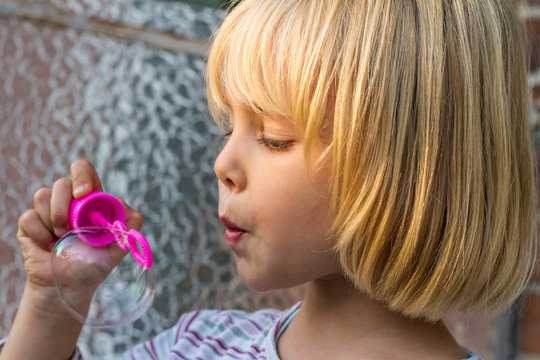 Portrait of little girl making soap bubbles