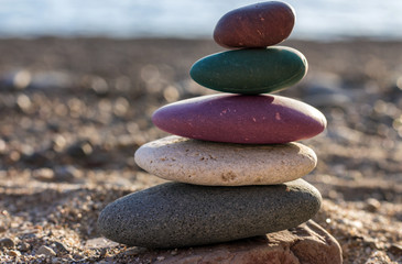 Fototapeta na wymiar Zen concept. The object of the stones on the beach. Against the sea and pebbles. Multicolor stones. Harmony & Meditation.