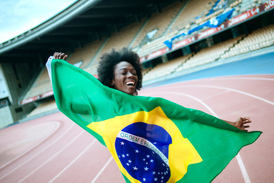 Young black athlete in stadium carrying Brazilian flag