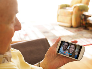 Grandfather videoconferencing with grandchildren via smartphone