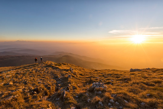 Italy, Marche, Monte San Vicino, two hikers looking at view at sunset