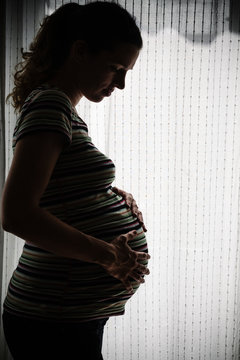 Pregnant woman against bright window