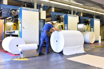 Man moving paper roll in a printing shop
