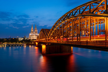 Cologne cathedral and Hohenzollern Bridge over Rhine river at dusk