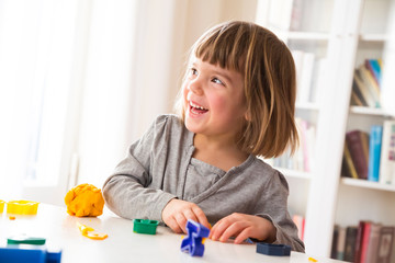 Little girl playing with yellow modeling clay