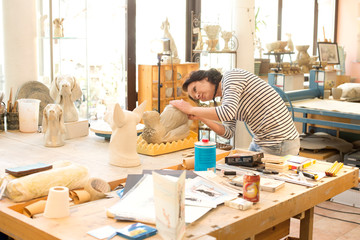 Potter in workshop working on dog figurine