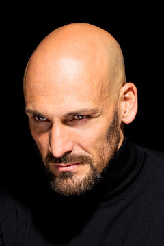 Portrait of angry man wearing black turtleneck in front of black background
