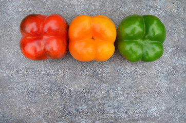 Multi-colored bell peppers on a grey background with copy space. Close-up, top view