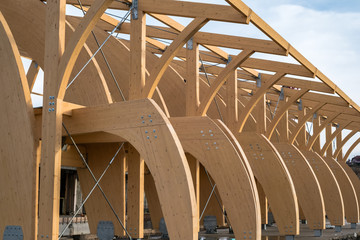 Detail of a modern wooden architecture in glued laminated timber on a blue cloudy sky