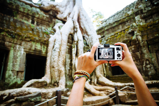 Cambodia, Angkor Wat, Woman takes pictures of the famous tree in Ta Prohm Temple