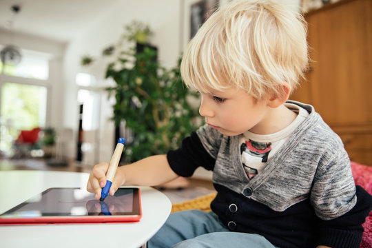 Little boy drawing with a digital pen on digital tablet at home
