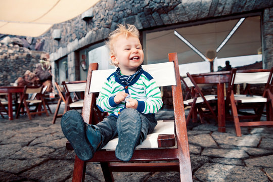 Spain, Lanzarote, laughing little boy sitting on a terrace of a restaurant
