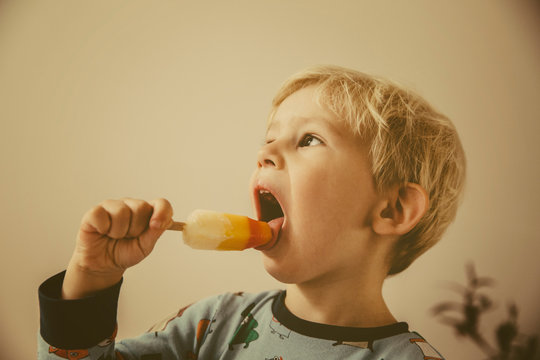Toddler licking popsicle at home