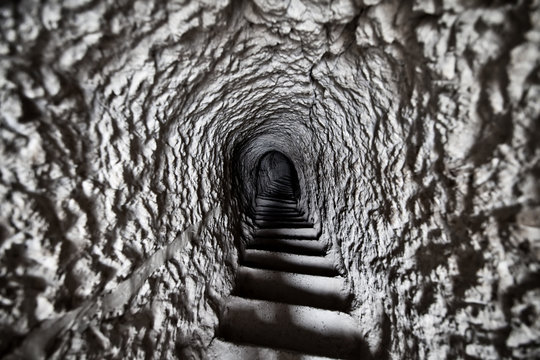 A staircase leading to a dark dungeon with stone walls.