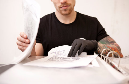 Tattooist with drafts in his tattoo studio