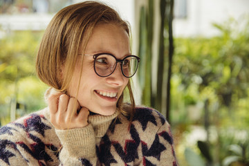Portrait of smiling young woman with glasses wearing fluffy sweater looking sideways