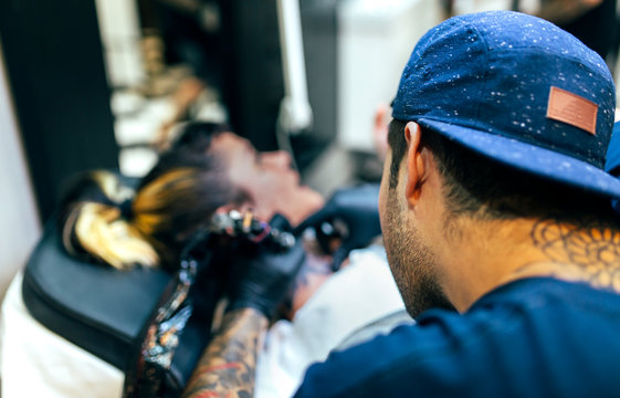 Woman receiving tattoo in tattoo studio