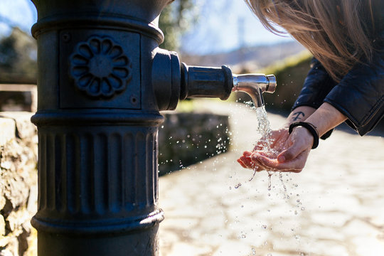 Young woman washing hands at a well