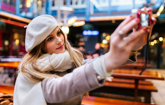 Young woman wearing beret taking selfie with digital camera